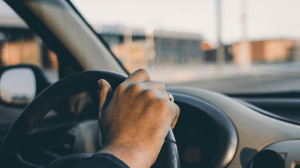 Man with wedding ring on holding a steering wheel